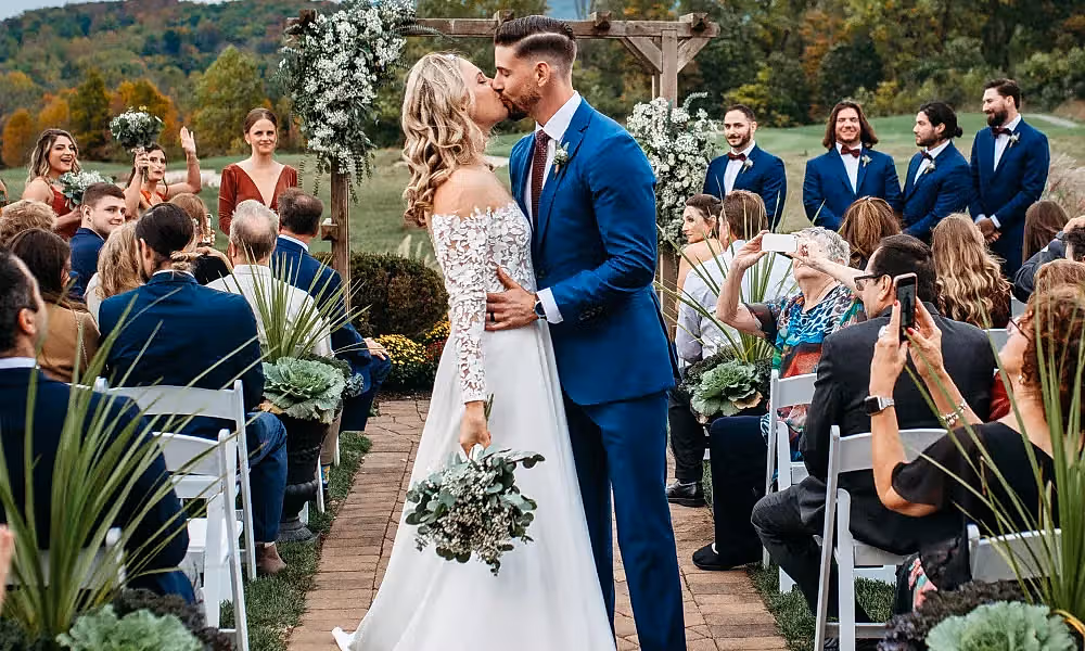 Bride and groom kiss while walking down the aisle at the Ballyowen wedding garden fall ceremony.