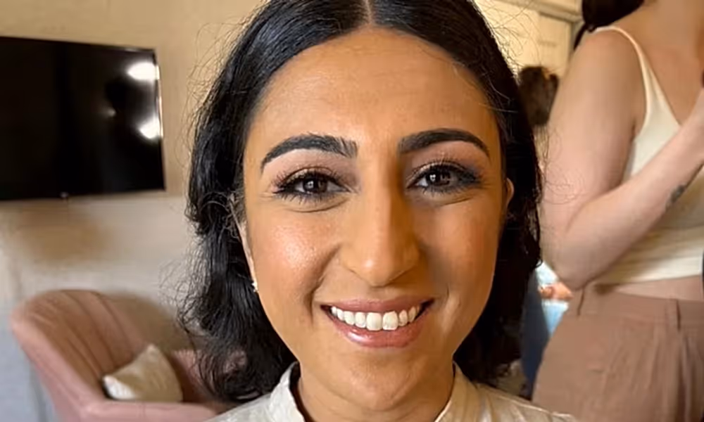 Woman, wearing white shirt, smiles at camera. 