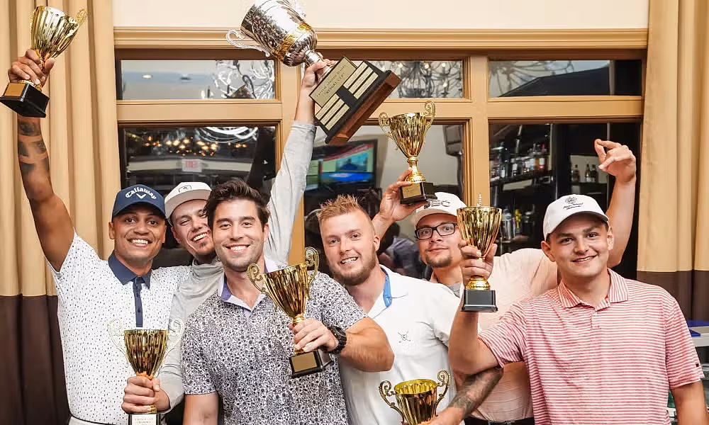 Group of men stand together with trophies. 