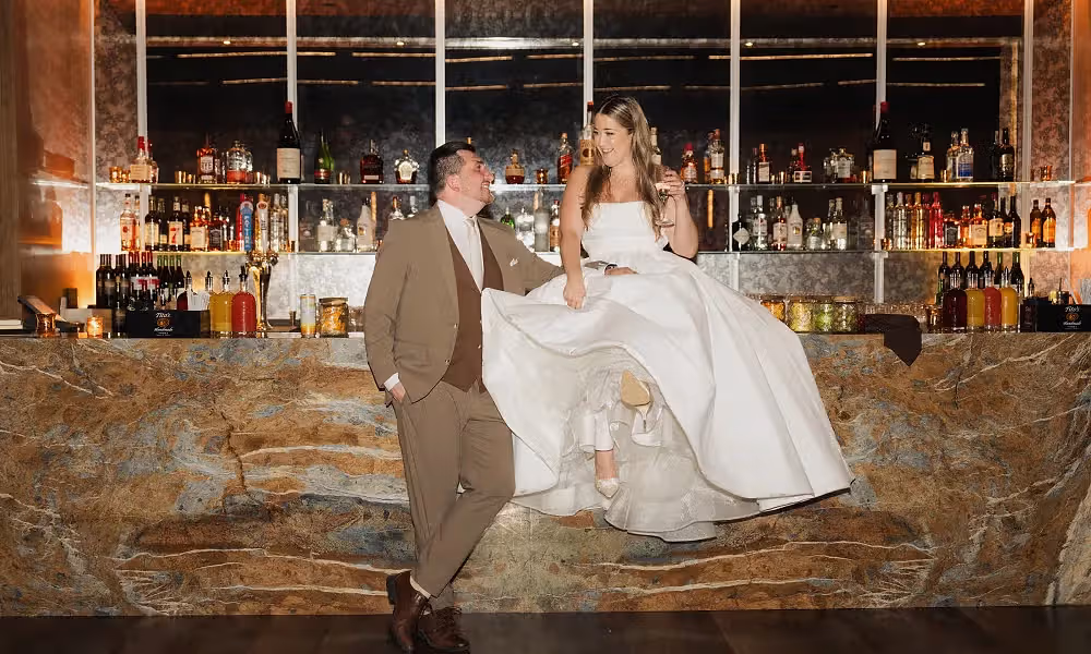Bride and Groom sit on bar in Canyon wedding. 