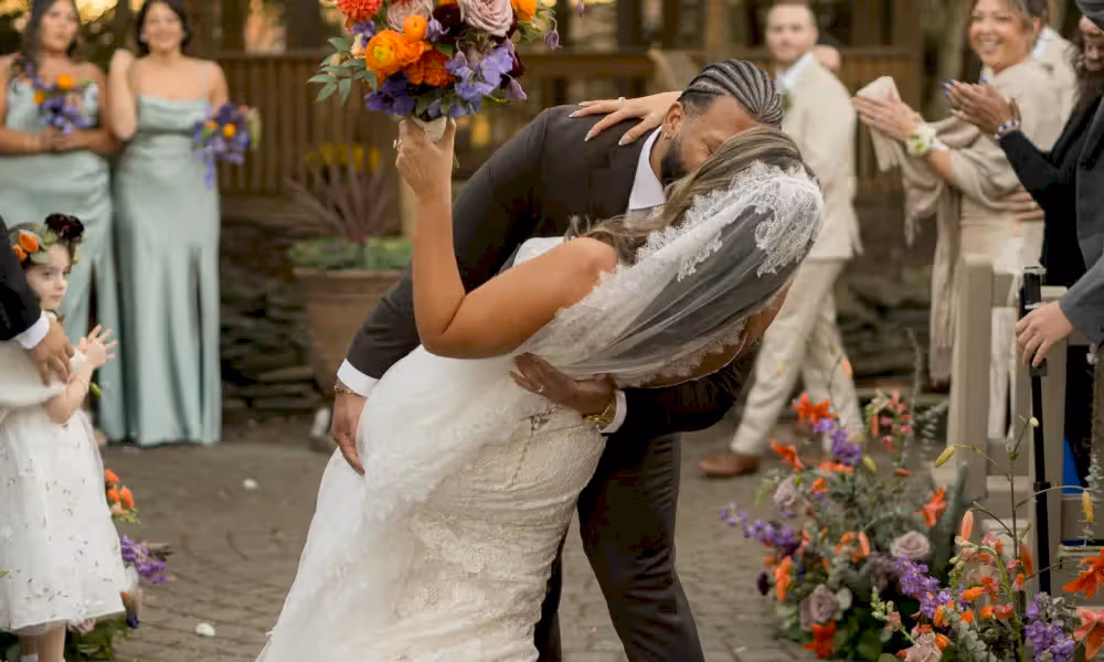 Groom dips bride and gives her a kiss as they walk back down the aisle at Black Bear wedding ceremony. 