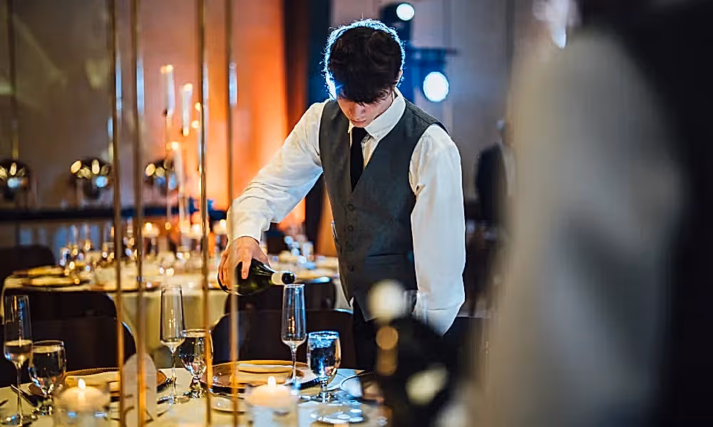 Canyon Ballroom server pouring champagne into glass.