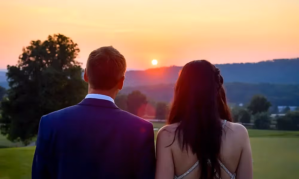 Bride and groom looking to the sunset on golf course