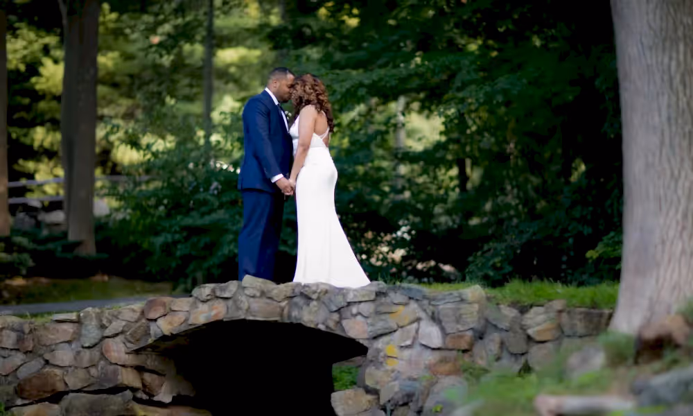 Bride and groom touching heads on bridge