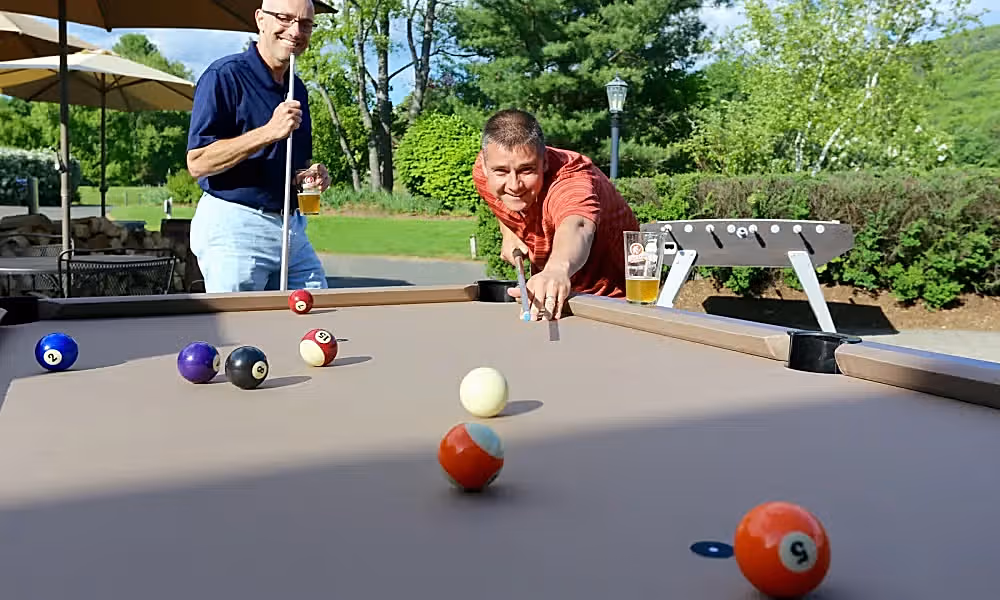 Couple of guys playing pool at the outdoor patio at Bear Den Grille