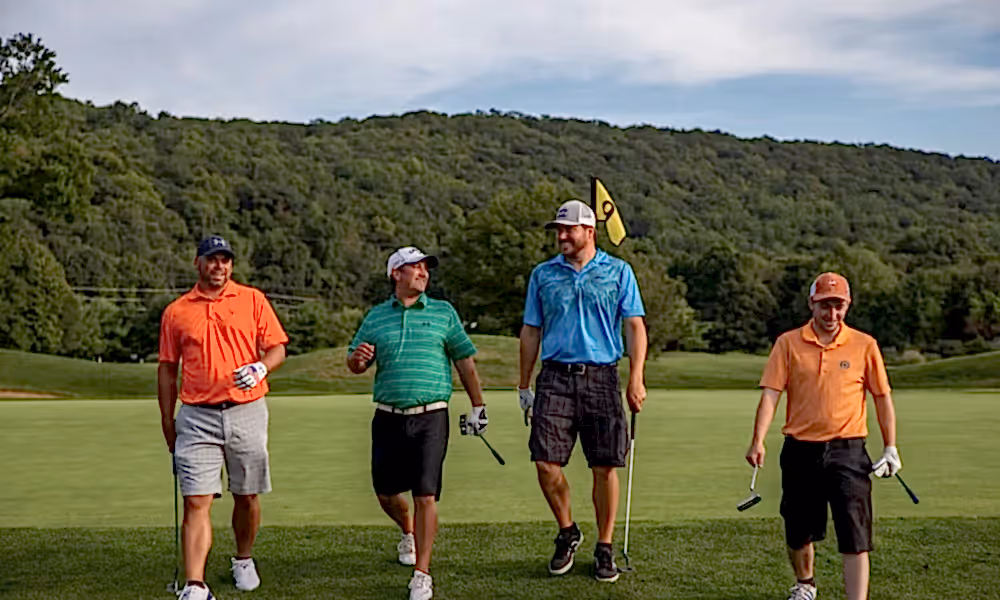 Four guys wearing multi-colored shirts walking on a golf course at a resort close to NYC
