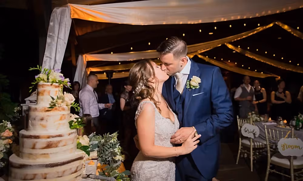 Bride and Groom kissing next to the wedding cake