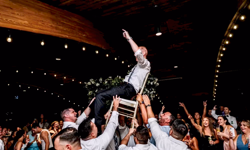 Groom raised on chair during wedding reception in Sweetgrass Pavilion