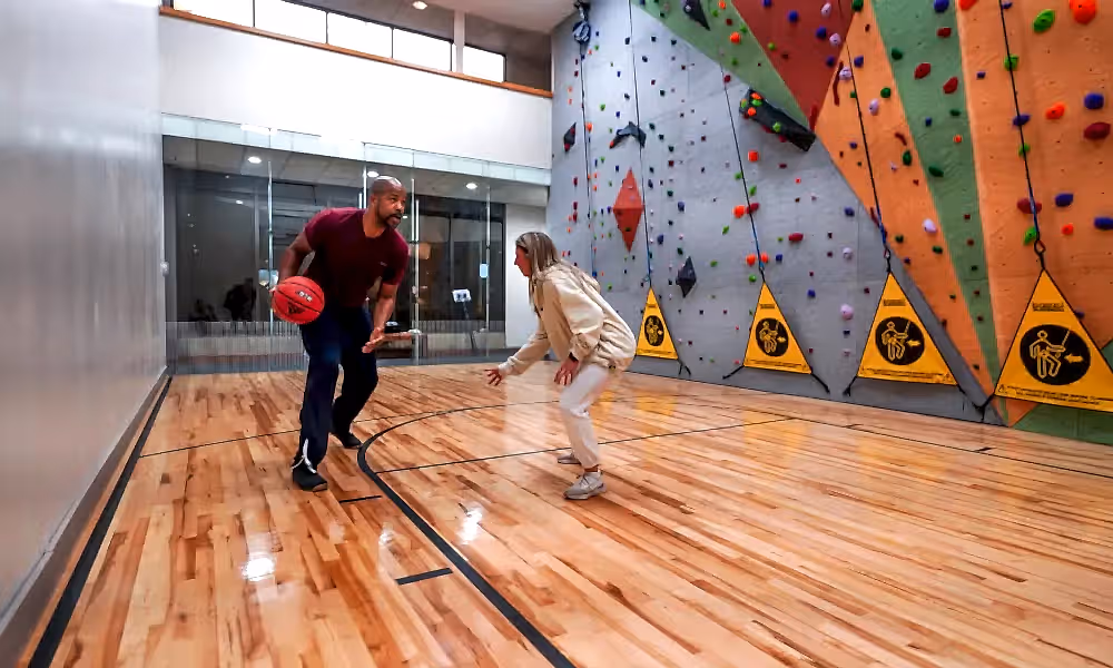 Two people playing basketball at indoor court.