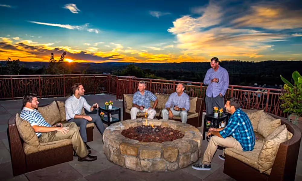 Group of guys sitting by a fire pit on the Fire and Water Terrace