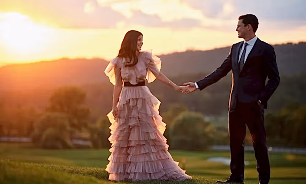 Bride wearing a pink wedding dress with groom on a golf course at sunset