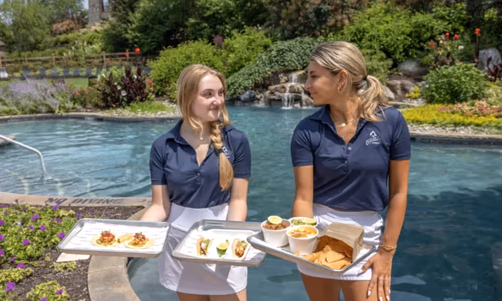 Taqueria waitresses holding plates of food at Biosphere pool.