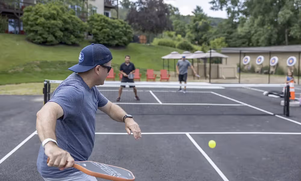 Man getting ready to hit ball over pickleball net.