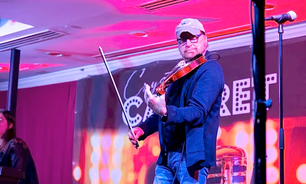 Man playing violin on Crystal Cabaret stage.