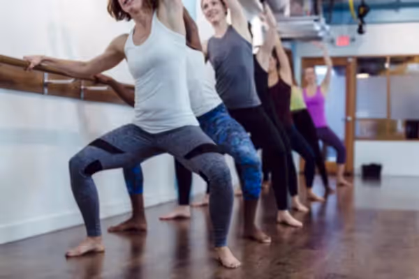 Women standing at ballet bar. 