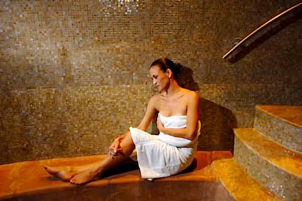 Woman in white towel relaxing in Elements Spa sauna.