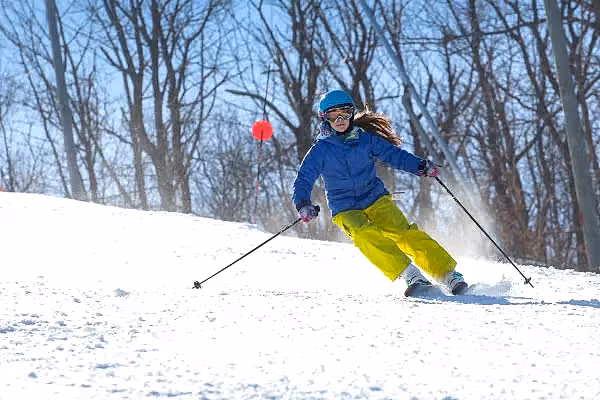 Person in blue jacket skiing down mountain.