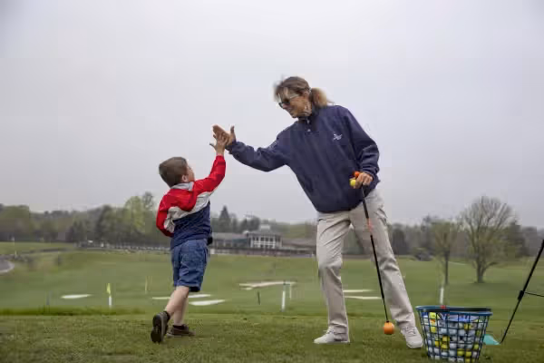 Young boy high-fiving after golf lesson