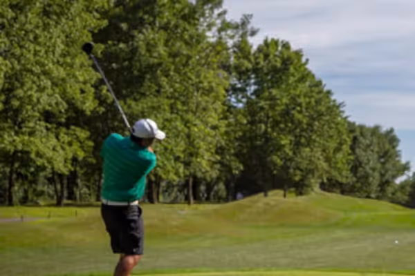 Golfer wearing a green shirt teeing off on Black Bear golf course