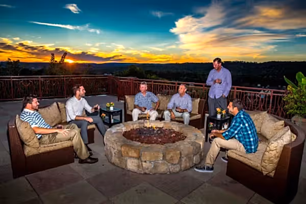Group of guys sitting by a fire pit on the Fire and Water Terrace