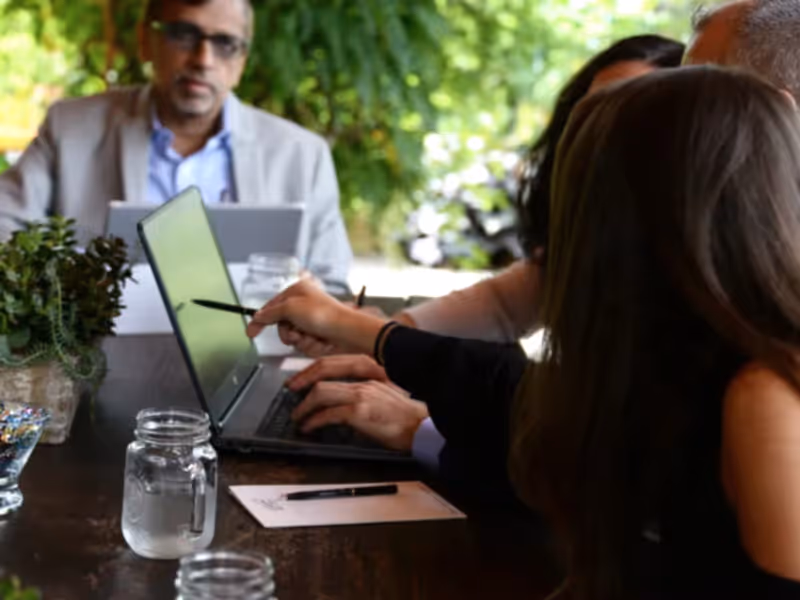 Guests sitting around table looking at laptop.