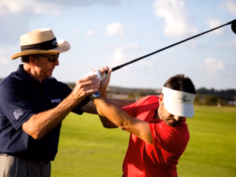 Golf instructor giving lessons to man in red shirt