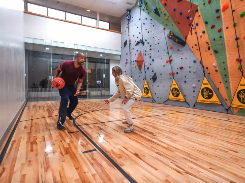Two people playing basketball at indoor court.